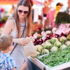 A mother and her son are shopping for fresh vegetables at a large farmers market
