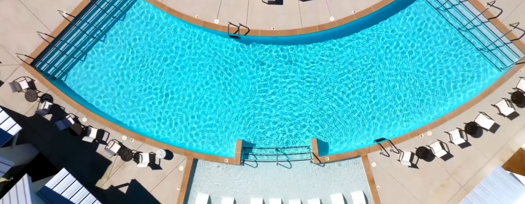 aerial view of a swimming pool with lounge chairs around it
